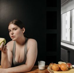 Woman enjoying an apple and glass of milk, promoting a healthy lifestyle indoors.